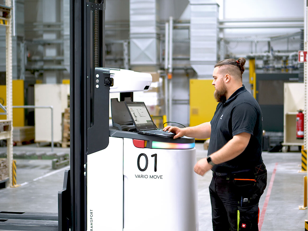 Ein Servicetechniker von ek robotics steht vor einem Transportroboter 